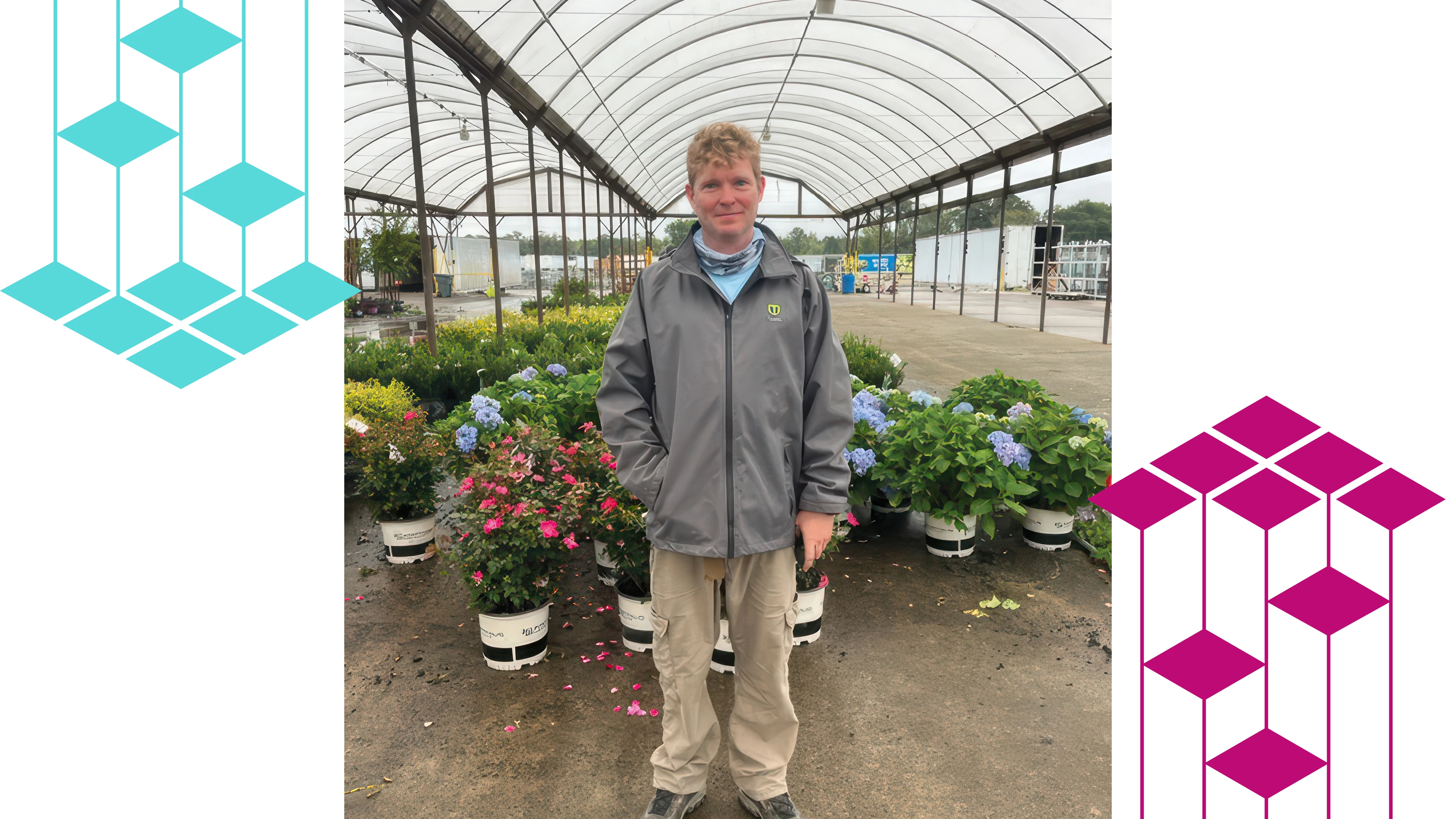 A man standing with potted plant inside a greenhouse.