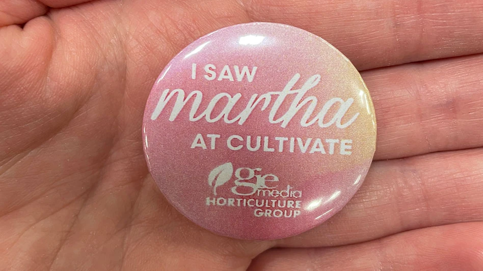 A hand holding a pink button with white text that reads I saw Martha at Cultivate GIE Media Horticulture Group.